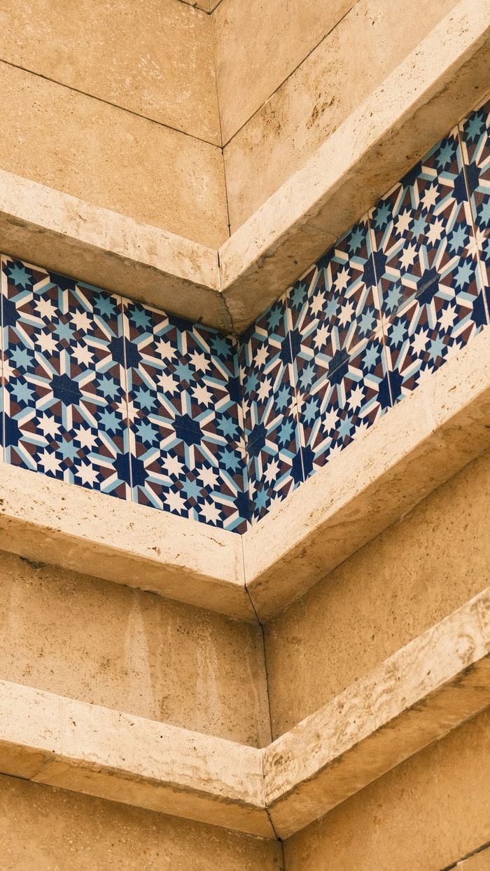 services-04 Close-up of geometric tile design on a beige building corner, showcasing intricate blue and white patterns.