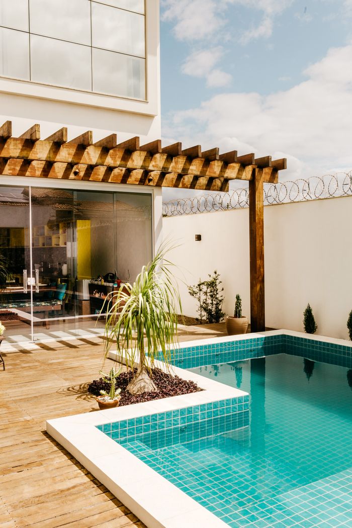 Mastering the First Impression: Your intriguing post title goes here Comfortable lounge area with swimming pool with clear water located on terrace near modern resort house in sunny day