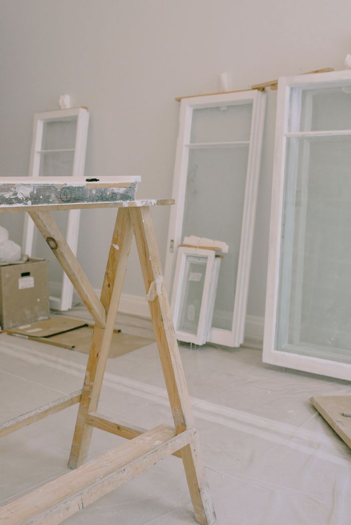 vision Interior of room with wooden workbench and windows removed from hinges with white frame placed near wall in light room during repair works