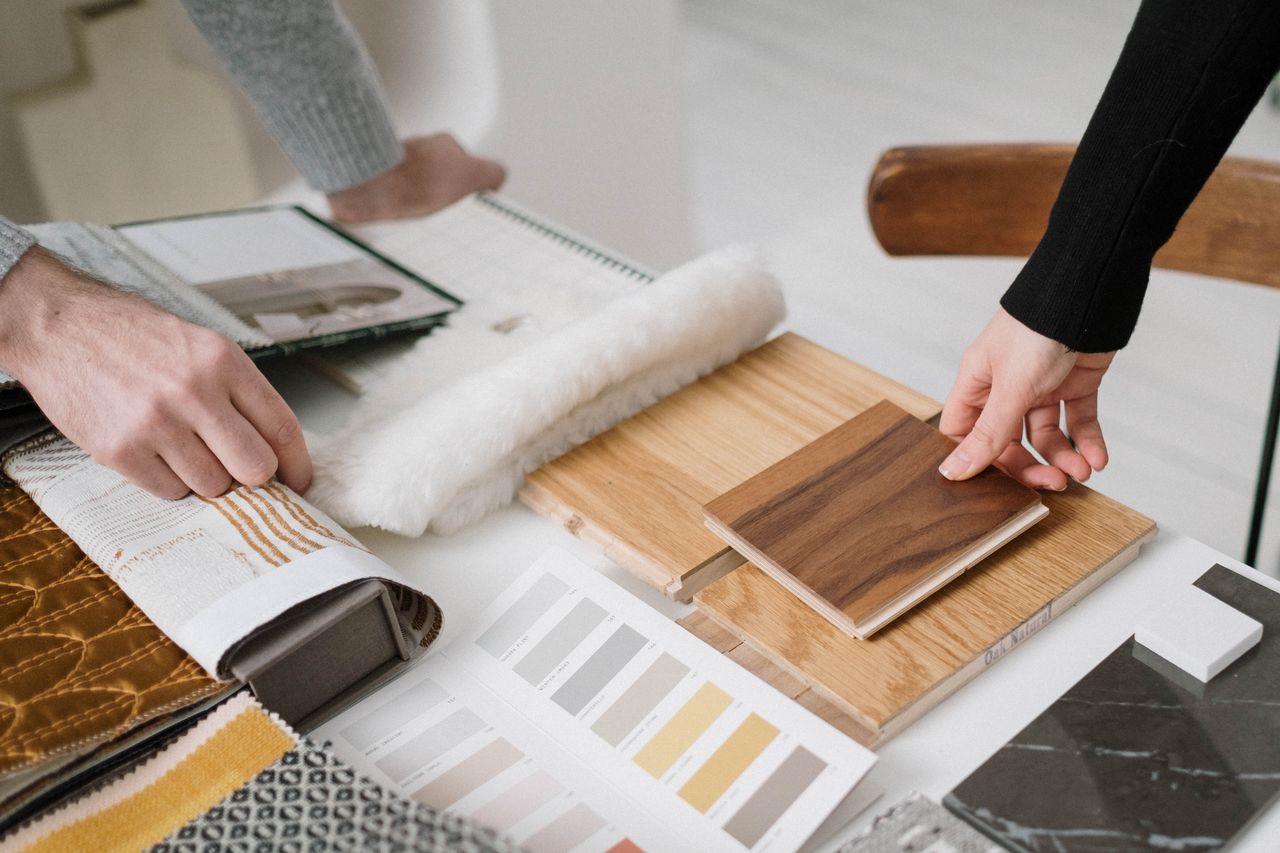 services-img Hands selecting and comparing textile and wood samples for interior design.