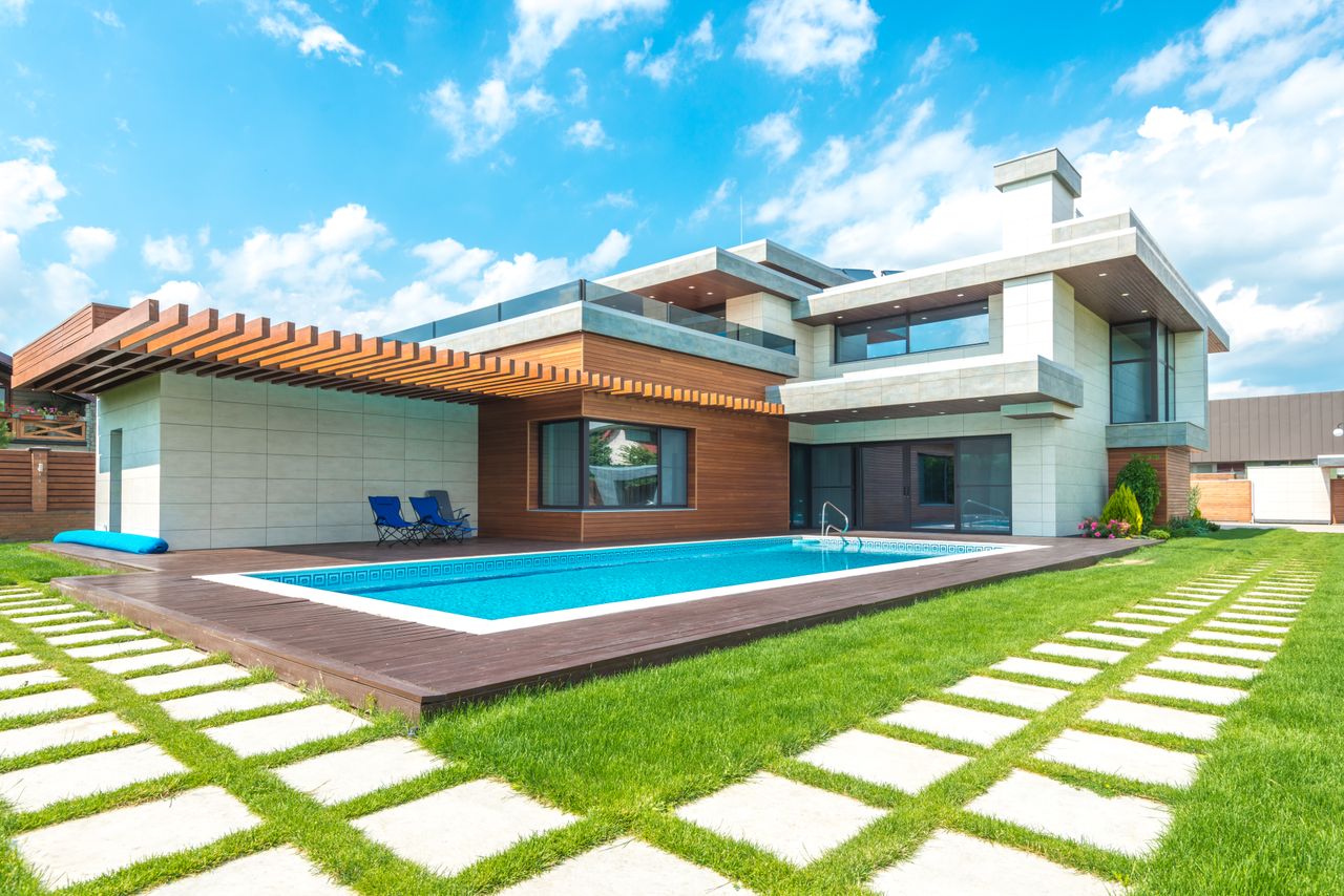 gallery-05 Contemporary house with pool, lush lawn, and clear skies.